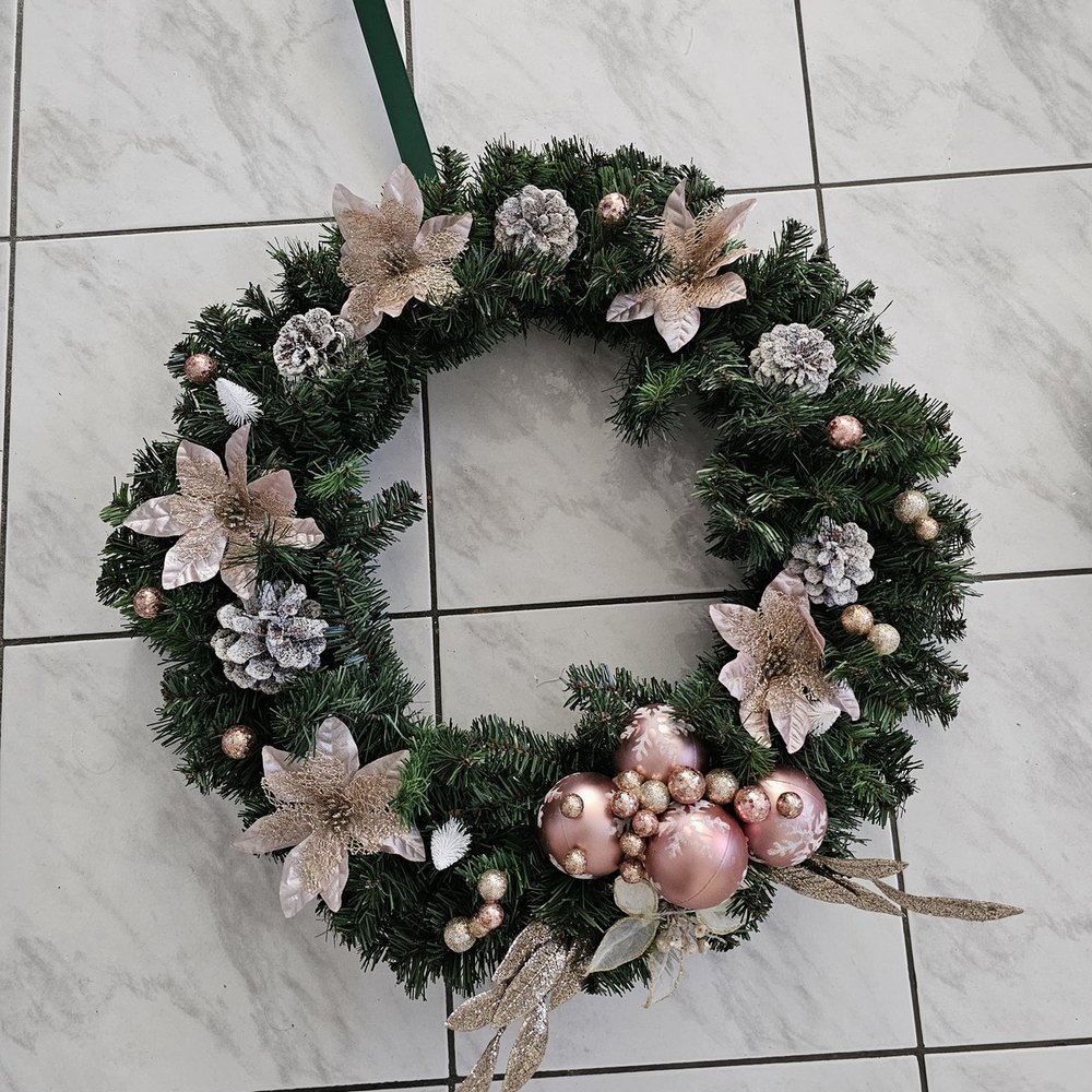 Handmade wreath with blush and champagne glitter poinsettias, snow-flocked pinecones and rose-gold ball ornaments