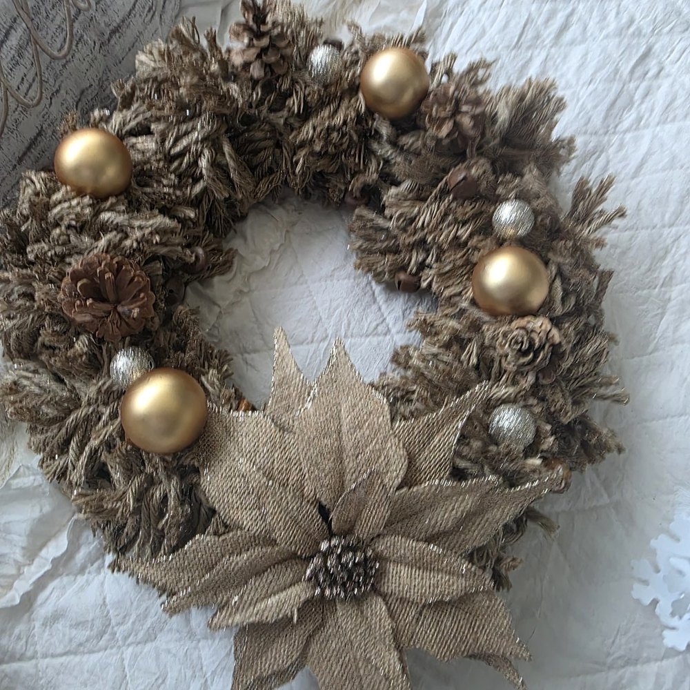Handmade rustic wreath of woven jute rope with a burlap poinsettia, real pinecones and gold ball ornaments