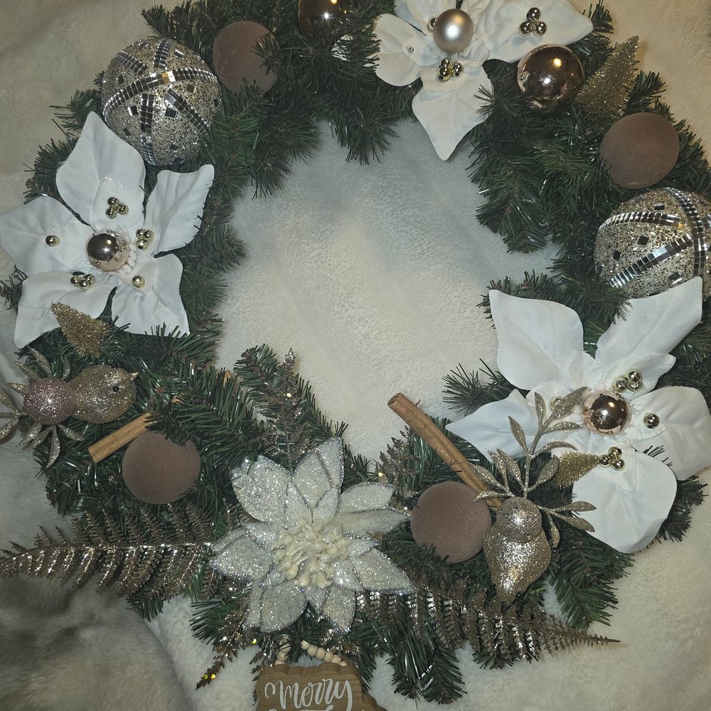 Handmade wreath with champagne ball ornaments, a white poinsettia, glitter birds, cinnamon sticks and a “Merry Christmas” tag