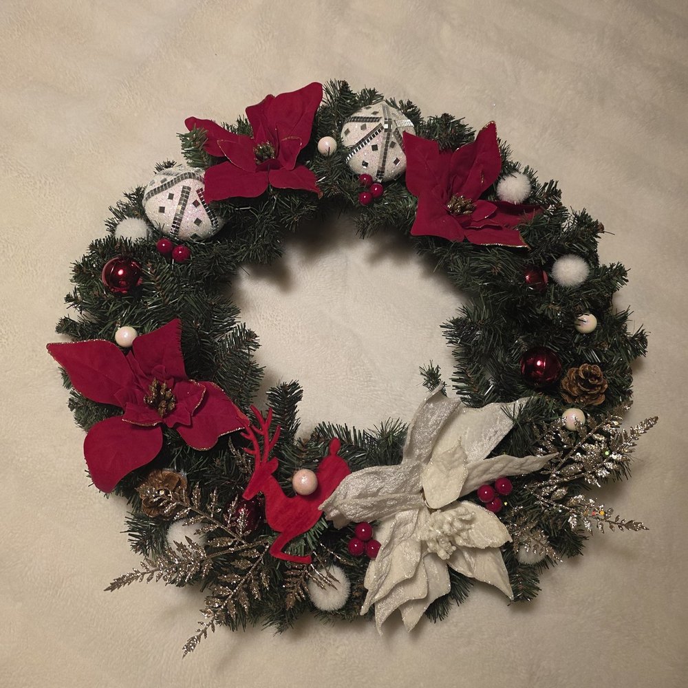 Handmade wreath with red poinsettias, a red wooden reindeer, silver mirrored ball ornaments and gold foliage