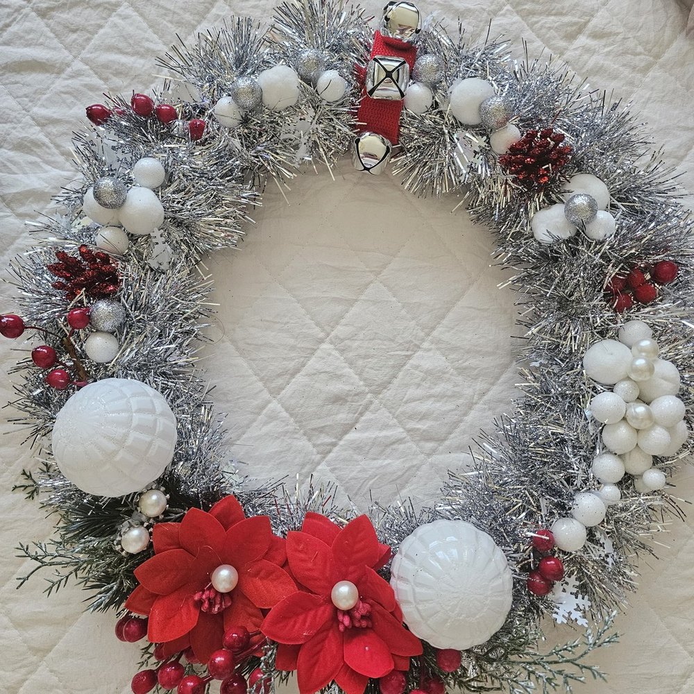 Handmade silver tinsel wreath with red poinsettias, jingle bells and red berries